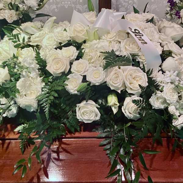 Large white floral casket spray with roses and lilies