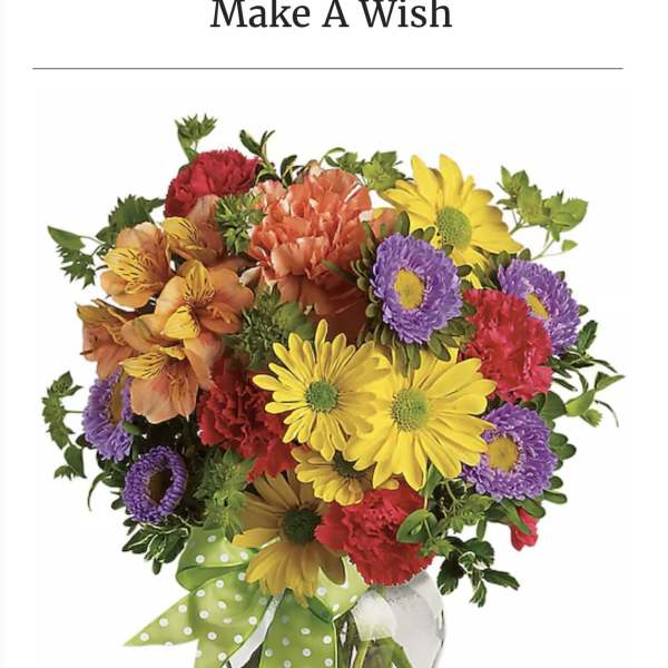 Colorful mixed bouquet in a clear glass vase with a green polka-dot ribbon