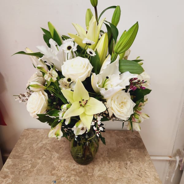 White lilies and roses arranged in a glass vase