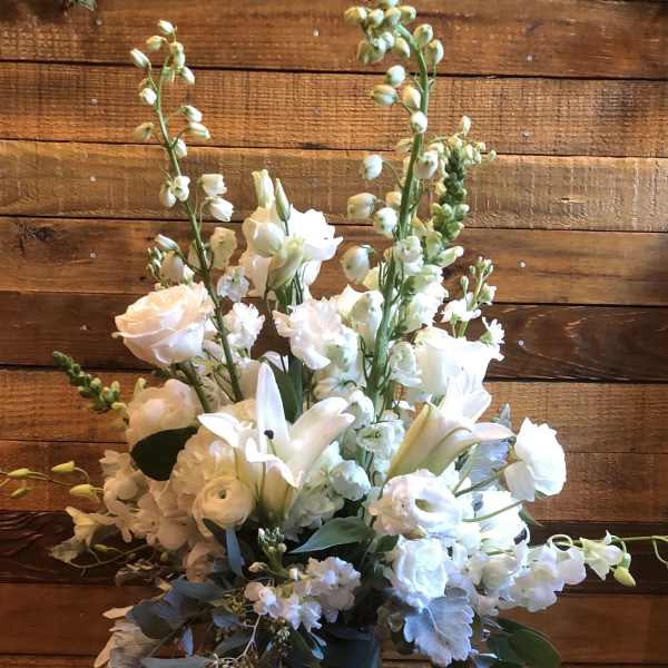 White floral arrangement in a clear glass vase with tall stems and mixed blooms
