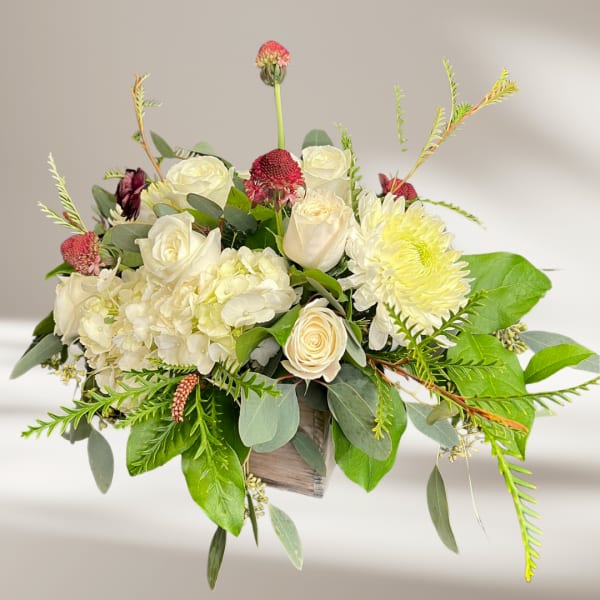 White roses and hydrangeas with yellow chrysanthemum in a wooden box