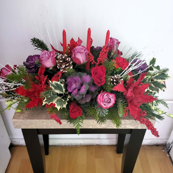 Festive floral arrangement with roses, candles, and pinecones on a table