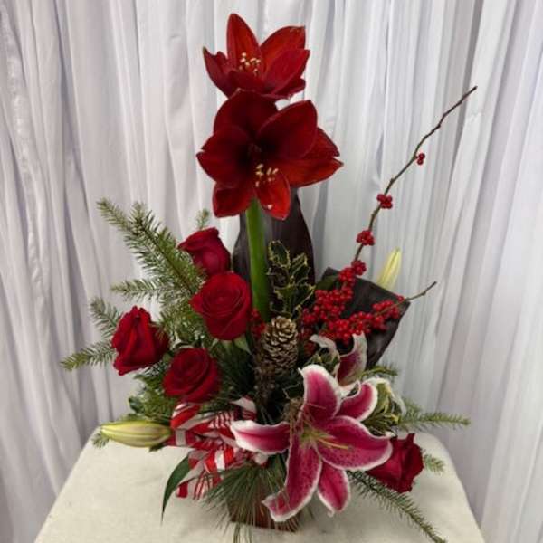 Red amaryllis and roses arranged with lilies in a vase