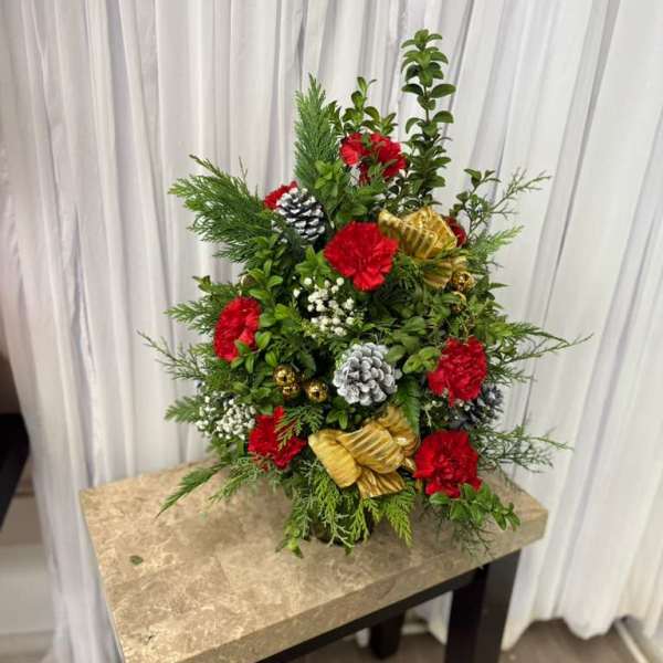 Christmas floral arrangement with red carnations, pinecones, and gold ornaments