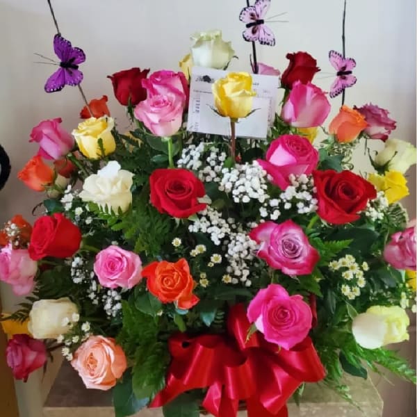 Large bouquet of multicolored roses with butterfly picks and a red ribbon