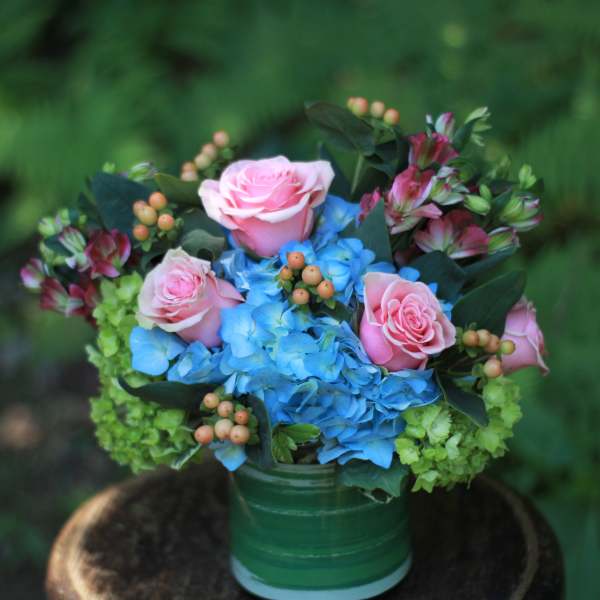 Pink roses and blue hydrangeas in a green vase