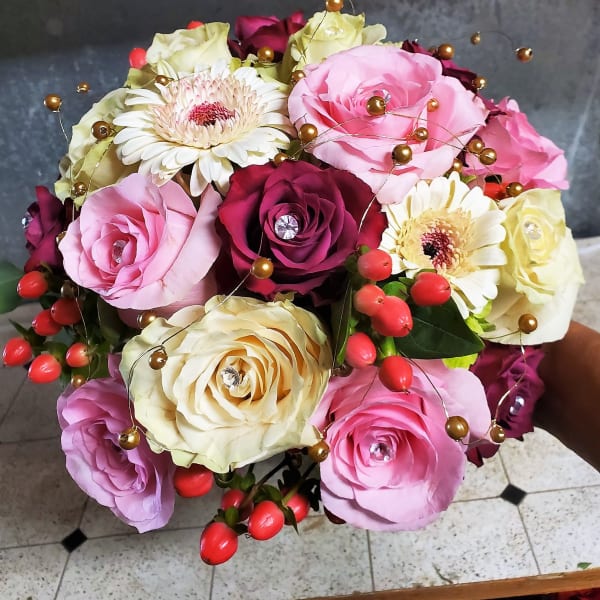 Bouquet of pink, cream, and burgundy roses with white gerbera daisies