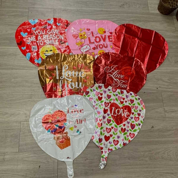 Assorted heart-shaped foil balloons with love messages on a floor