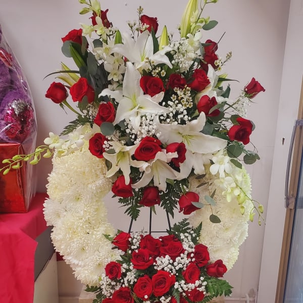 Standing floral tribute with red roses, white lilies, and white chrysanthemums