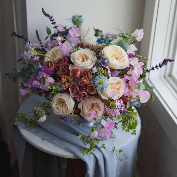 Loose bouquet of cream and pink roses with purple accent flowers