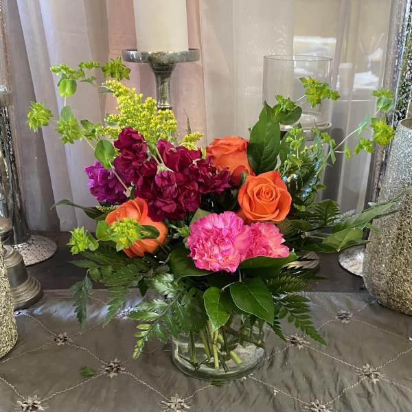 Mixed bouquet of orange and pink flowers in a clear glass vase