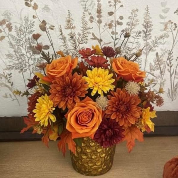 Orange and yellow floral arrangement in a gold vase