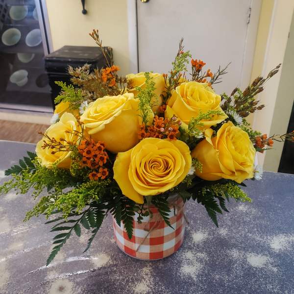 Yellow roses arranged in a checkered box with orange accents