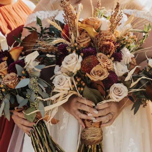 Three bridal bouquets with roses and dried grasses
