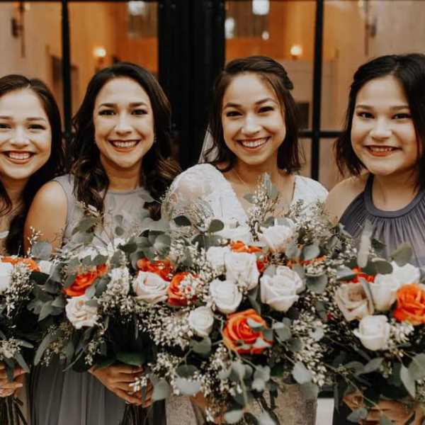 Four women holding orange and white rose bouquets