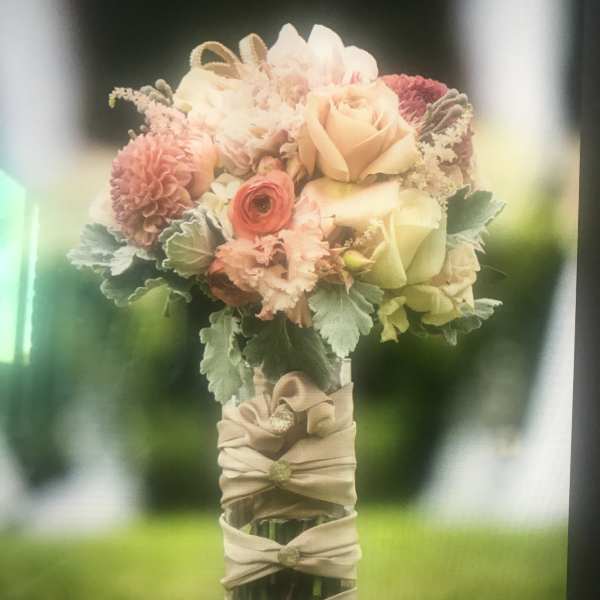 Hand-tied bouquet of blush and peach flowers with a wrapped handle