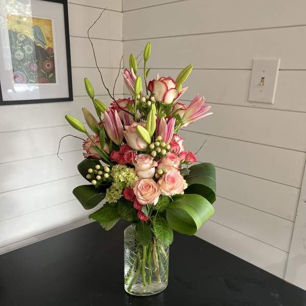 Pink roses and lilies arranged in a clear glass vase