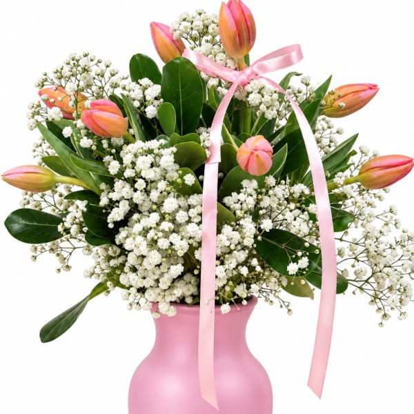 Pink tulips and white baby's breath in a pink vase with a ribbon