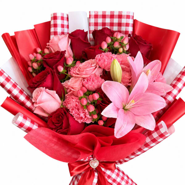 Bouquet of pink and red roses with lilies and carnations wrapped in red paper