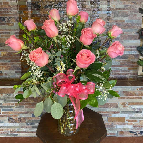 Pink roses in a clear glass vase with a pink ribbon