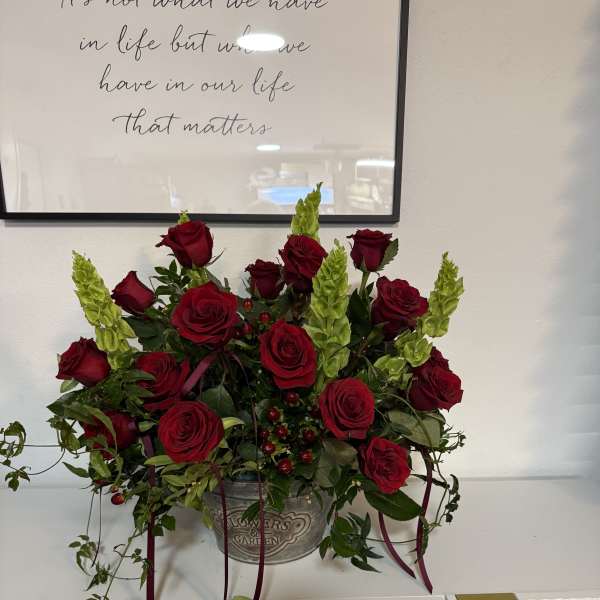 Red roses and green spikes arranged in a metal container