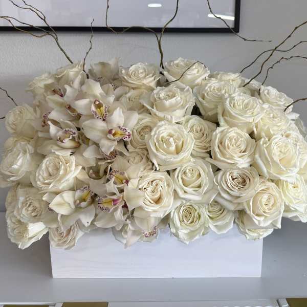 White roses and orchids arranged in a rectangular white box