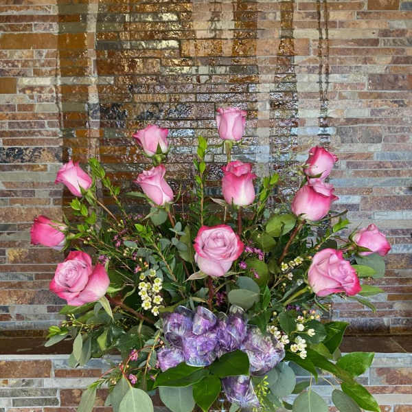 Pink roses arranged in a clear glass vase with greenery