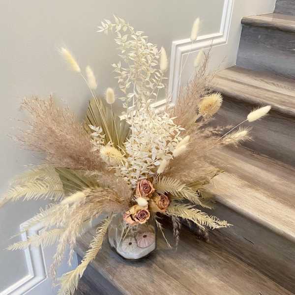 Dried floral arrangement in a small vase on a staircase
