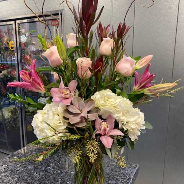 Tall mixed floral arrangement in a clear glass vase with pink and white blooms