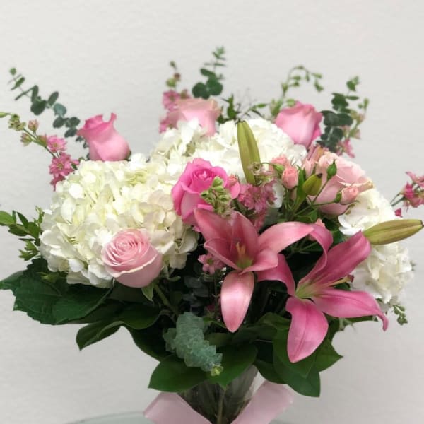 Pink lilies and roses with white hydrangeas in a glass vase
