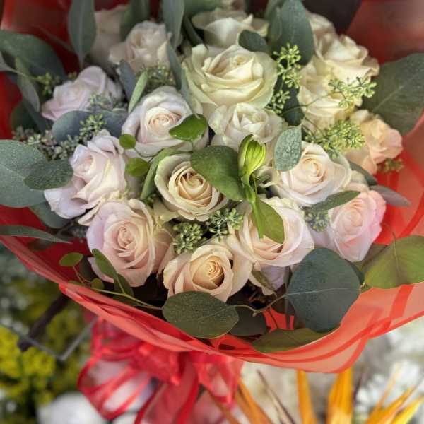 Bouquet of pale roses wrapped in red paper