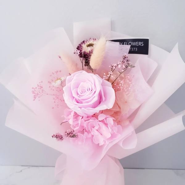 Pink rose bouquet with hydrangea and delicate filler flowers wrapped in pale pink paper