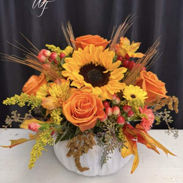 Orange and yellow floral arrangement in a white pumpkin vase