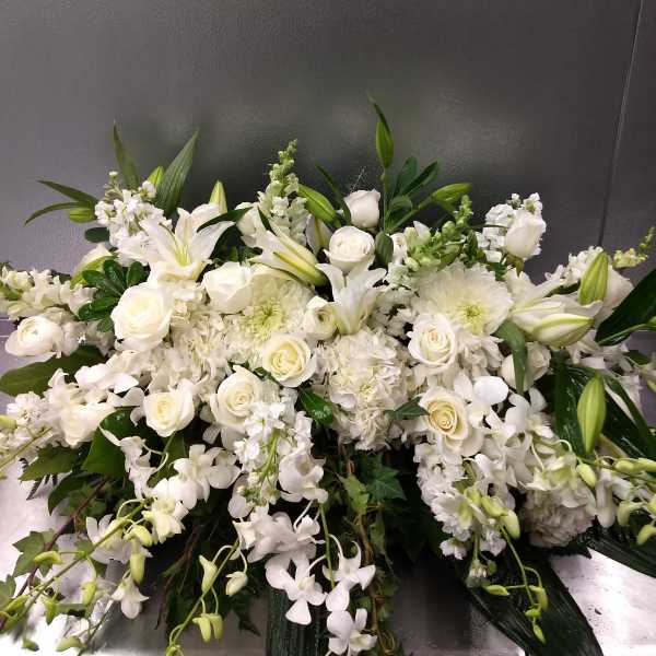 Large white floral arrangement with roses, lilies, and orchids