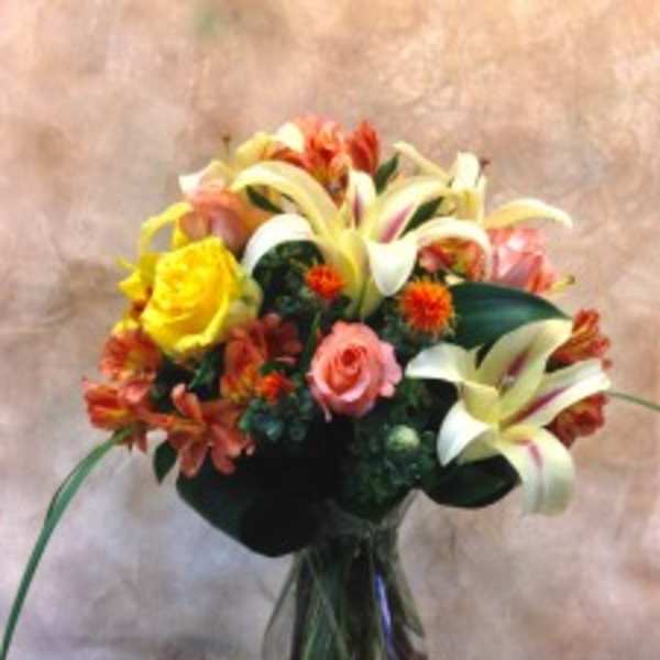 Bouquet of lilies, roses, and orange flowers in a glass vase