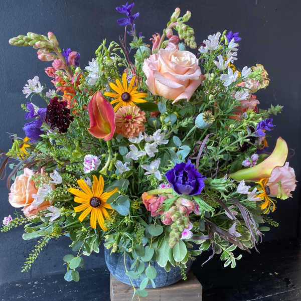Mixed bouquet with peach roses, purple blooms, and yellow daisies in a vase