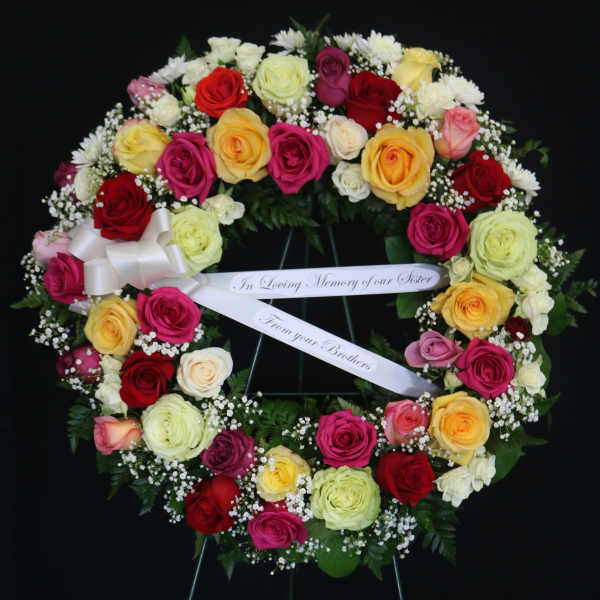 Heart-shaped wreath of multicolored roses with a memorial ribbon