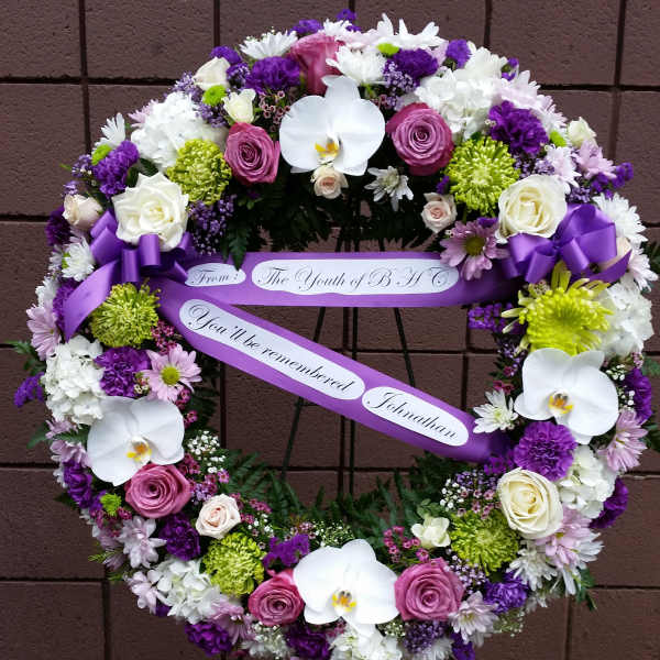 Heart-shaped floral wreath with purple ribbon and white orchids