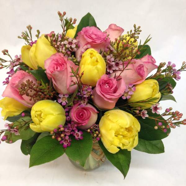 Bouquet of pink roses and yellow tulips in a glass vase