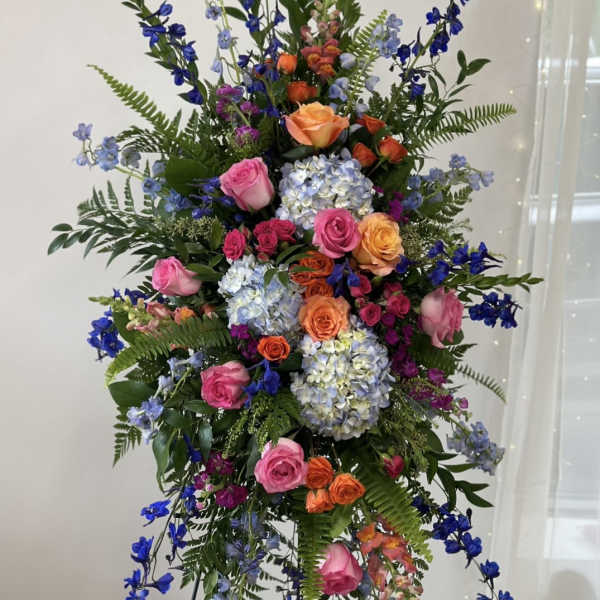 Tall standing floral spray with pink, orange, blue, and lavender blooms