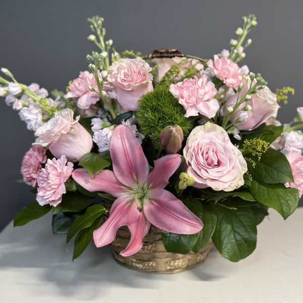 Pink roses and lilies arranged in a low basket