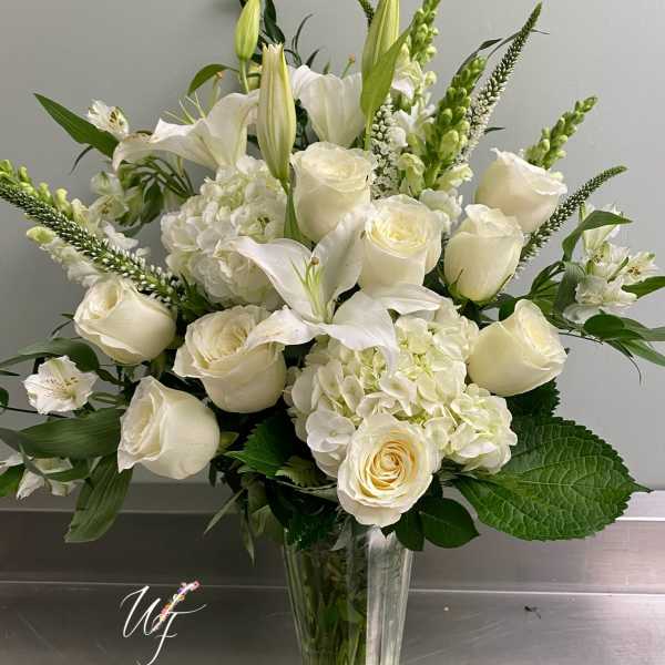 White roses and lilies arranged in a clear glass vase