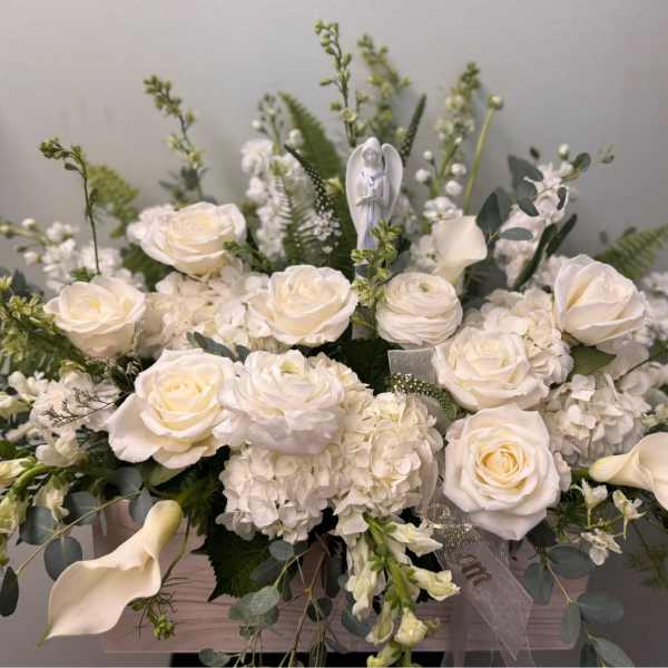 White roses and calla lilies arranged in a low box with greenery.