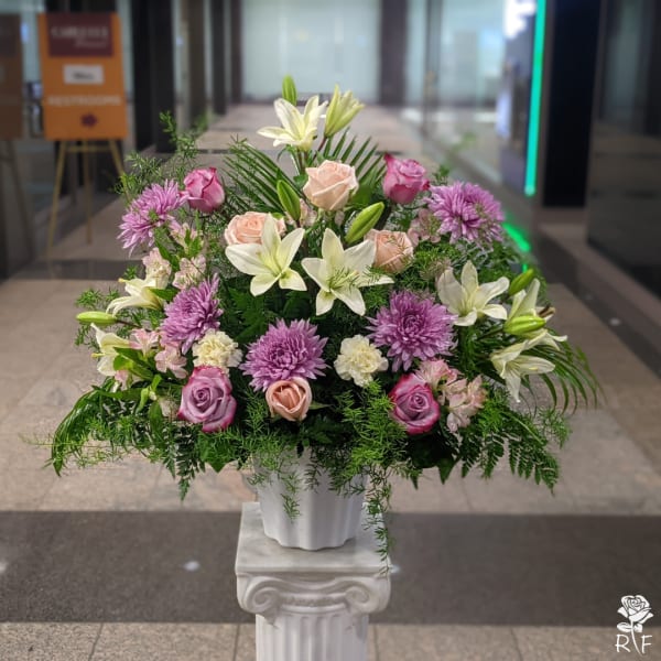 Mixed bouquet of lilies, roses, and purple chrysanthemums in a white vase