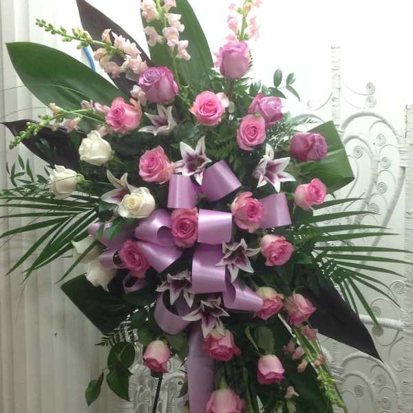 Tall standing floral spray with pink and white roses and lilies, accented by a lavender ribbon