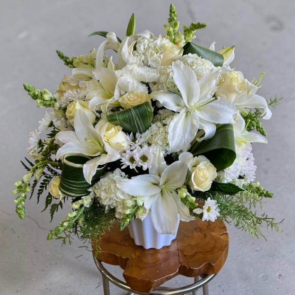 White lilies and roses arranged in a white vase