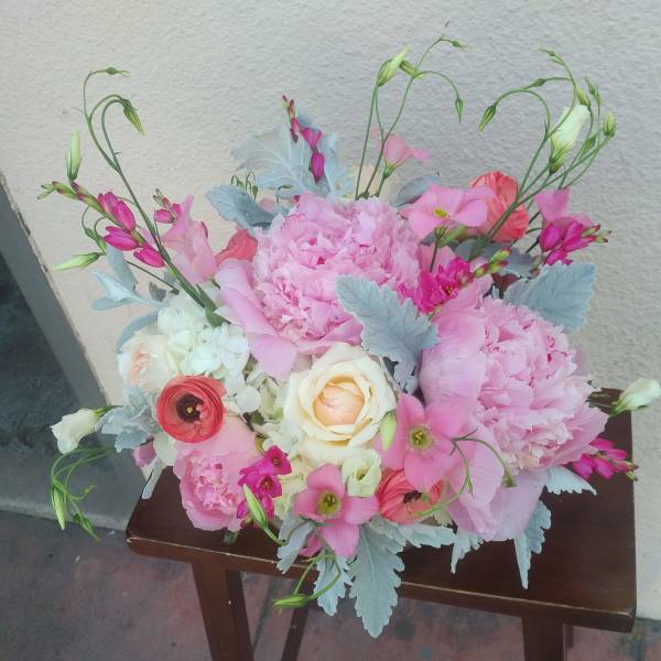 Pink floral arrangement with roses and peonies on a small table