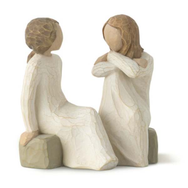 Two carved figurines of girls in cream dresses sitting together