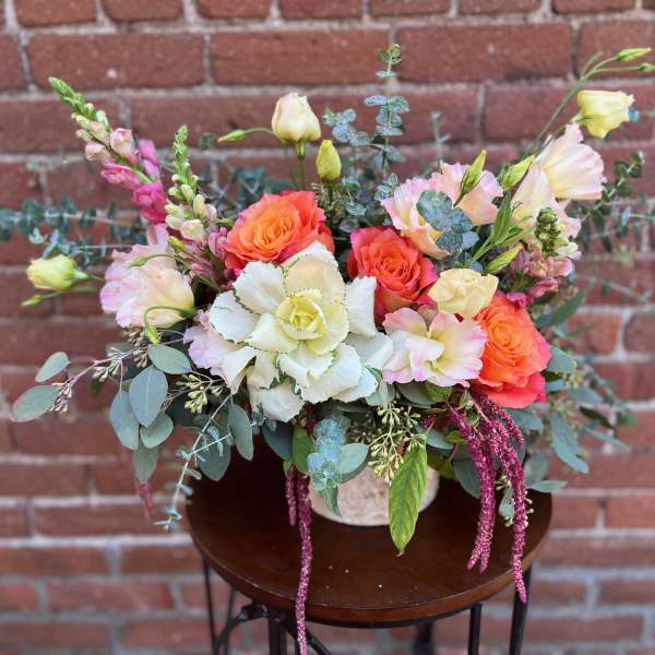 Mixed bouquet of coral and white flowers with eucalyptus in a vase
