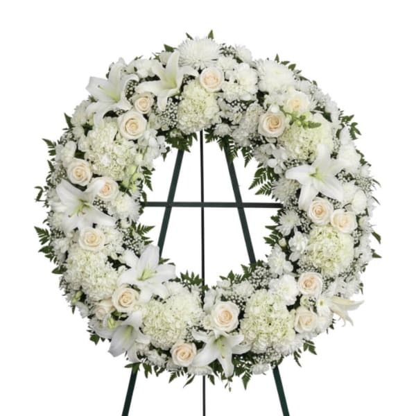 White funeral wreath with lilies, roses, and chrysanthemums on a stand